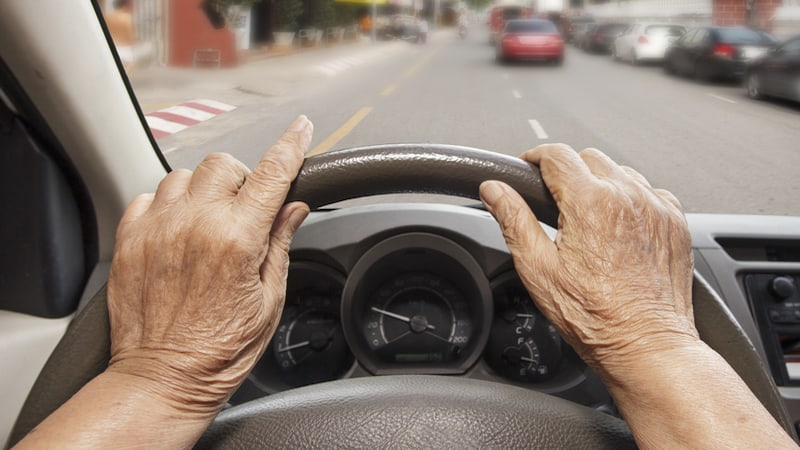 Wrinkled hands on a steering wheel - Senior Driving Car In City Photo By Toa555 Dreamstime. For article, Seniors Guide offers seven driving safety tips for seniors and touches upon options if the tips are not enough to guarantee road safety.