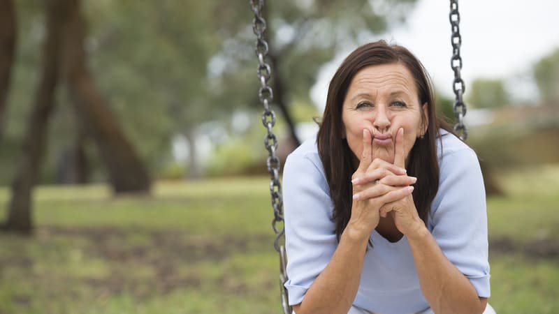 woman on swing pondering question - photo by Robert Bayer, Dreamstime. A woman questions dividing an estate among her three grown children: based on how they treat her or a three-way split? “Ask Amy” weighs in.