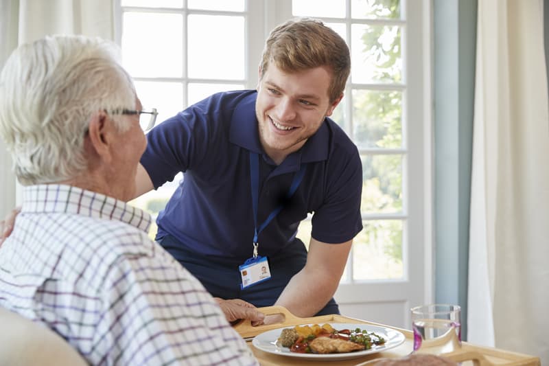 Older man at home being cared for by a home care nurse. Photo by Monkey Business Images, Dreamstime. A NORC, naturally occurring retirement community, serves older adults. Its services offer a blueprint for aging-in-place options.