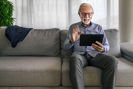 Older man at home on his couch using his table for video calling. From MoonSafarii