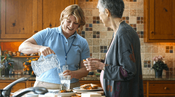 Home health aid pouring senior a glass of water