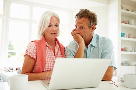 Couple looking concerned at a laptop.
