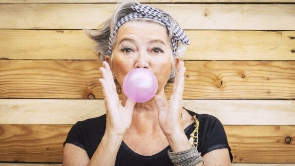 A fun woman blowing a bubble with chewing gum.