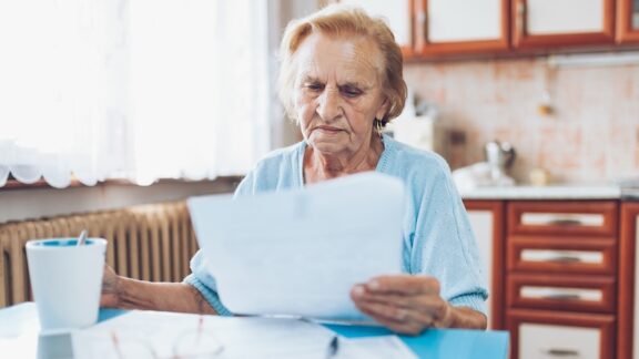 Woman looking at papers in financial stress because of social insecurity.