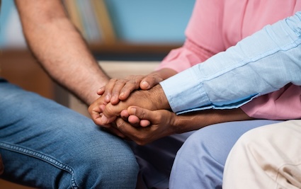 A son holding his parents' hands because he worries about his aging parents' anxiety.
