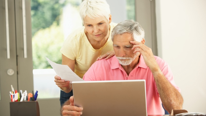 A senior couple at their computer trying to figure out why one isn't getting Getting Retroactive Social Security Benefit Payments