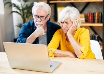 A puzzled senior couple on their laptop computer. They should be getting Getting Retroactive Social Security Benefit Payments but aren't