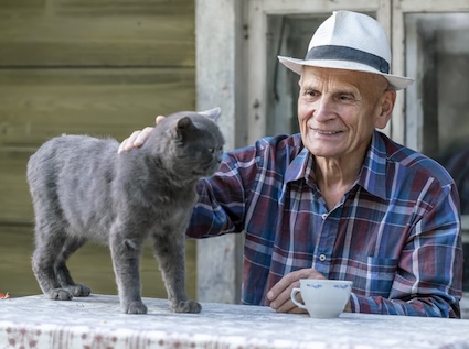 An older man with a cat on a table outdoors - with pets to take care of, we still matter. Image by Yaroslaf