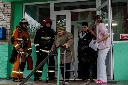 Firefighters stand by as a resident with a walker is part of a fire evacuation drill, considering fire safety at senior living communities. Image by Kusmina Svetlana