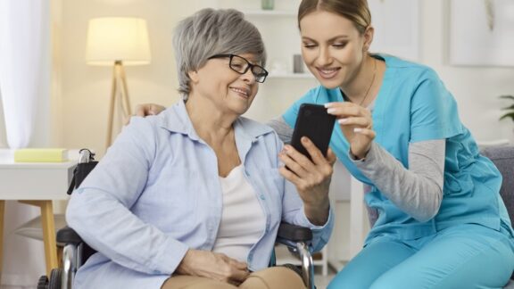 Woman on the phone with home care professional beside her.