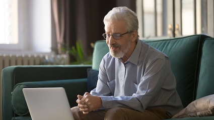 Man talking with someone on the computer because he knows the correlation of loneliness and longevity.