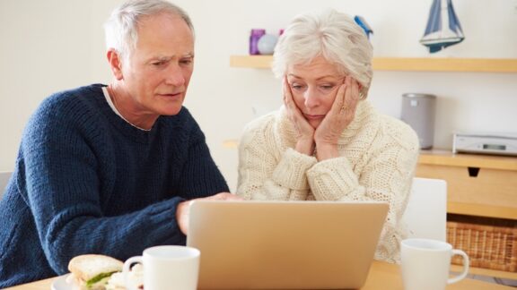 A worried couple on a computer wondering if they should take social security early.