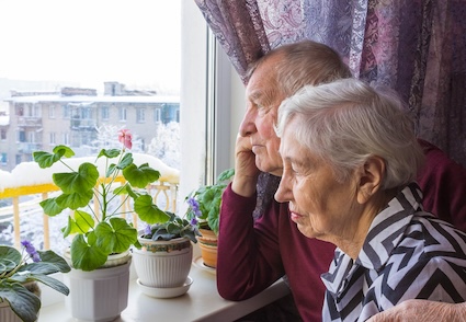 Sad couple looking out of window since they're estranged with their daughter.
