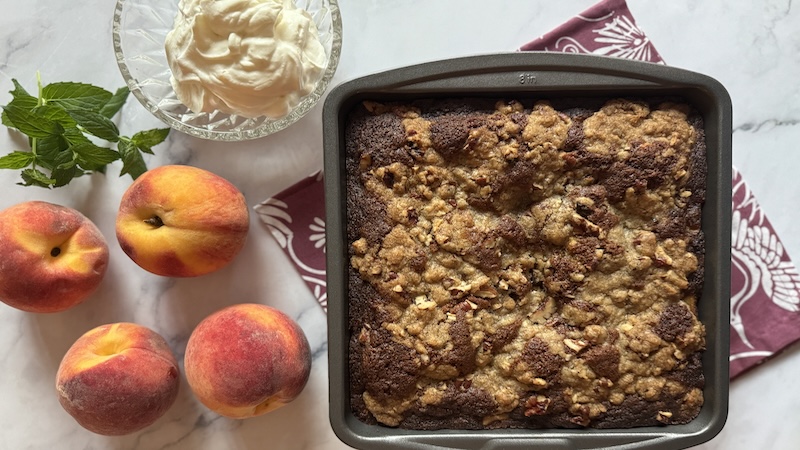 A peach pecan cardamon cake alongside peaches
