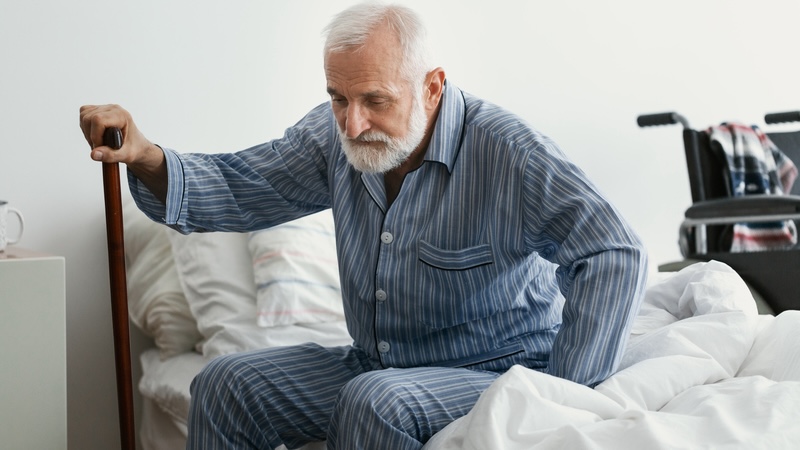 A weak senior man struggling to stand up from his bed. Is he ready for a disaster or does he need emergency preparedness planning for seniors? Image by Katarzyna Bialasiewicz