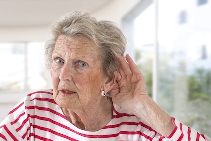 Woman with her hand to her ear struggling to hear without her hearing aids.