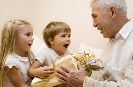 Two grandchildren give a gift to their grandfather, hoping their parents know the best gifts for seniors. Image by Alexey Kuznetsov