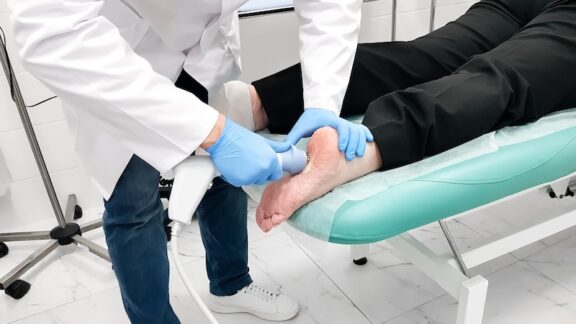 A senior receiving shockwave therapy for foot problems.
