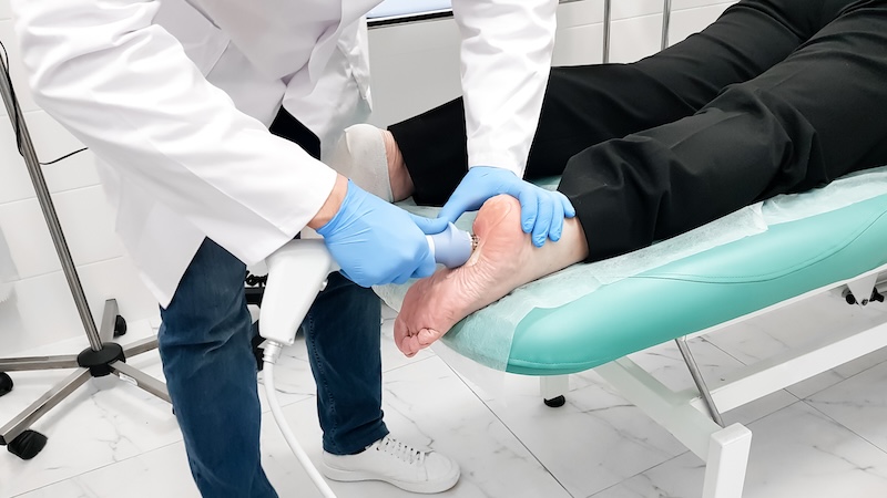 A senior receiving shockwave therapy for foot problems.