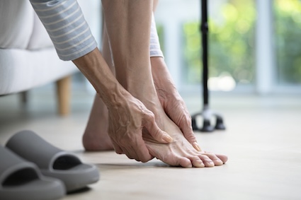 A woman on couch experiencing foot pain.