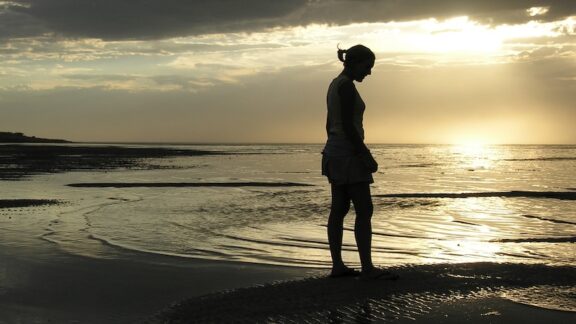 Lonely woman on a beach craving connection after retirement.