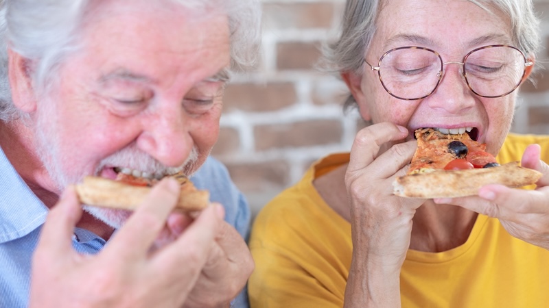 Couple eating a pizza even though it will zap your energy