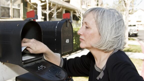 A senior woman checks her mailbox. Since Social Security ends paper checks, she will not be able to receive her monthly payment by mail. Image by Spectruminfo