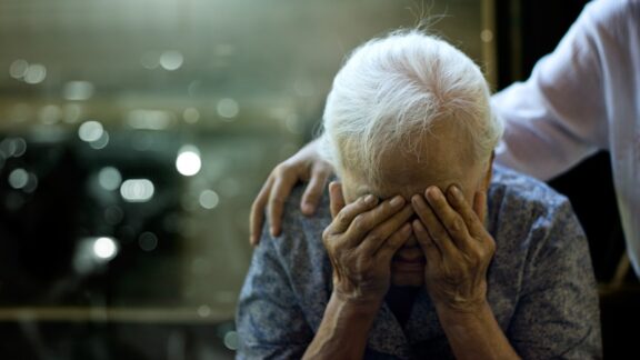 A caregiver comforts an elderly person. Knowing the 7 stages of dementia before death can help in managing the challenges. Image by Pop Nukoonrat.