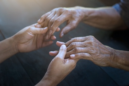 Younger hands grasping older hands. Knowing the 7 stages of dementia before death can help in managing the challenges. Image by Pop Nukoonrat.
