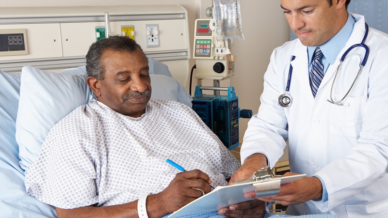 Patient in a hospital being shown paperwork by his doctor, demonstrating the importance of documenting your medical history. Image by Monkey Business Images
