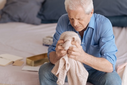 A grieving man holds his wife's sweater, grappling with losing a life partner. Image by Dmytro Zinkevych