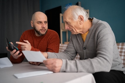Son helping elderly father with financial caregiving