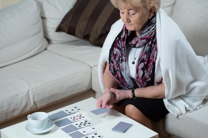 Woman playing solitaire, experiencing the incontinence and loneliness link. Image by Bialasiewicz.