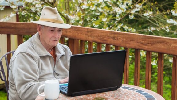Man outside with coffee and a laptop participating in an online support group.