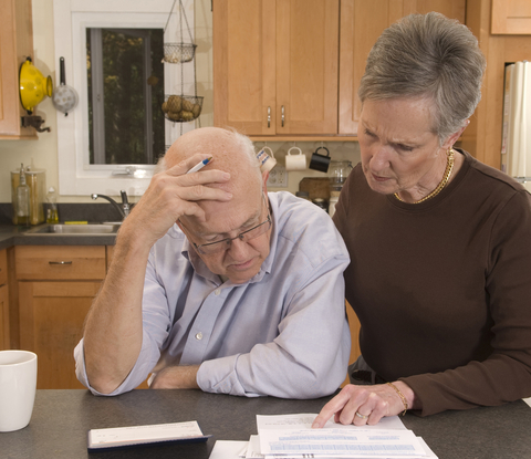 A couple is concerned about their finances, looking at bills and how the 2026 Social Security COLA is insufficient