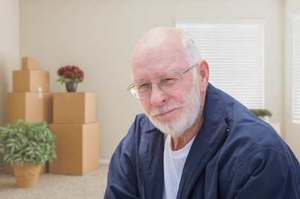 Man contemplative as he sits in front of boxes packed as he's ready to go.