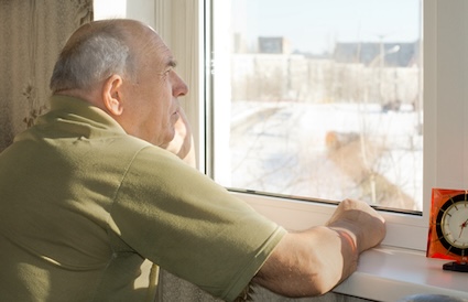A lonely man at home looks out of his window. Image by Kolotype. Emphasizes the importance of checking in on seniors