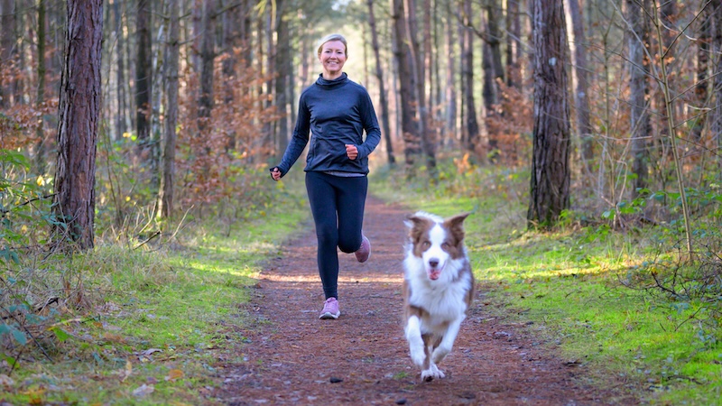 Woman running with her dog, showing benefits of pet-friendly exercise trends.