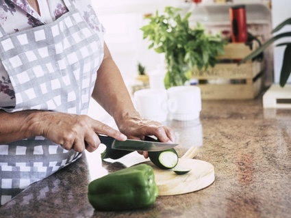 woman slicing squash in her kitchen. Image by Simona Pilolla.