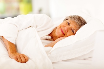 Happy senior in bed has overcome the issues of aging and sleep. By Hongqi Zhang.