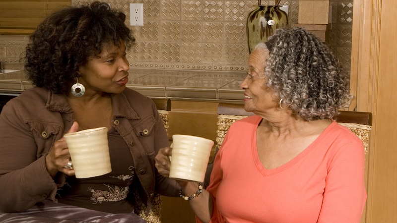 African American woman drinking coffee with her elderly mom even though it hurts your wallet.