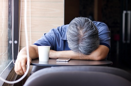 Man with head down on desk because he got insufficient sleep.