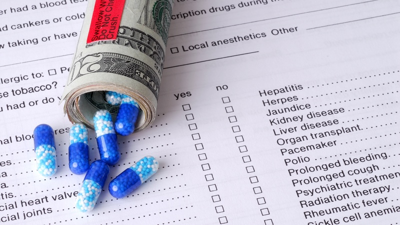 A roll of 20-dollar bills with capsules spilling out, by Stevies. The high cost of prescription drugs in the U.S. causes sticker shock, challenges seniors’ budgets, and sometimes even means avoiding doctor-recommended treatments. Alexandra Robertson of Visory Health suggests ways to reduce prescription drug costs.