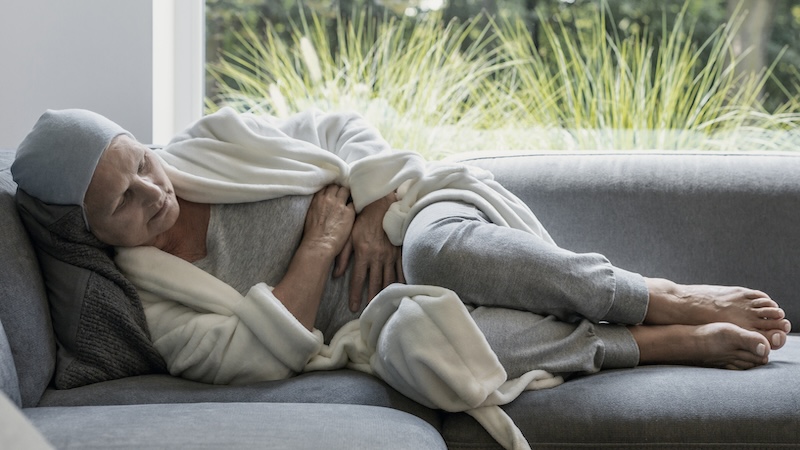 Woman dealing with cancer lying on the sofa at her home. Article on online care coordination tools.