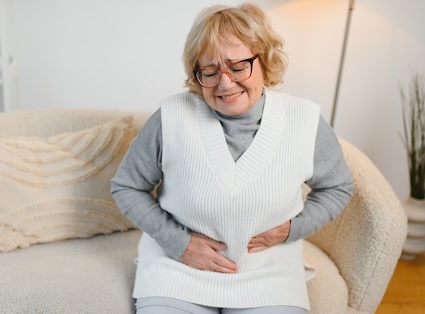 Woman in pain holding her stomach showing signs of food poisoning.