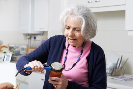 An older woman uses a gadget for tackling hard-to-open packaging such as a tightly sealed jar. Image by Ian Allenden