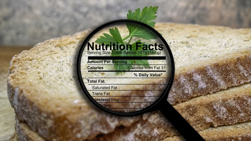 A magnifying glass observing nutrition facts on grocery store bread.