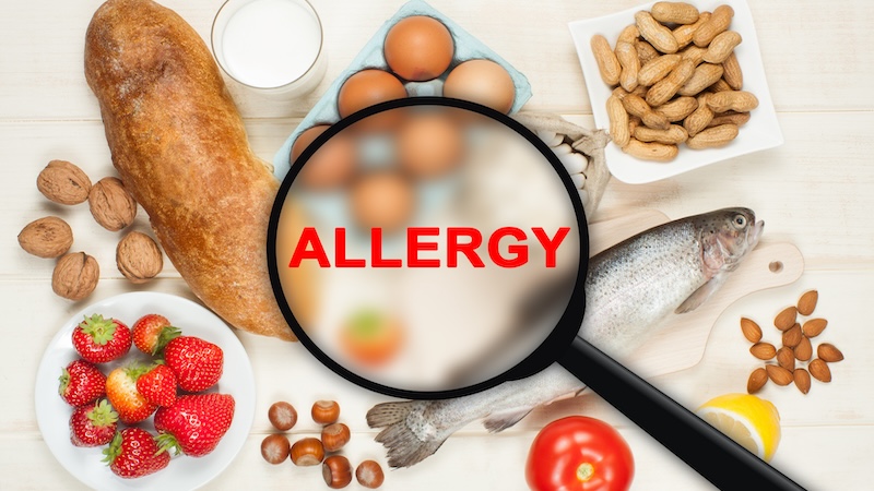A magnifying glass looking at food that says "food allergies"