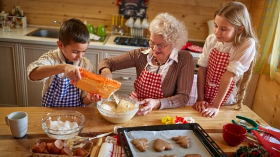 Grandmom who knows the benefits of holiday traditions is making Christmas cookies with her grandkids. Image by Igor Mojzes