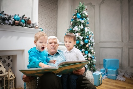 Granddad reading a holiday story to his grandsons reflects the benefits of holiday traditions. Image by photobac